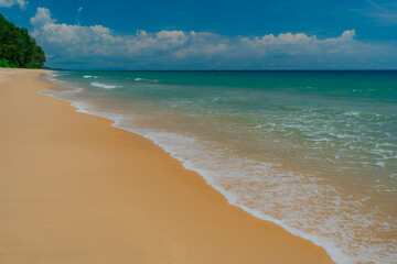 Minimalist surf study captured in razor-sharp detail: lace-fine foam traces a clean curve across warm, velvety sand as the water shifts from translucent aqua to deep sapphire on the horizon, offering 