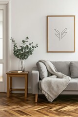 Modern living room with gray couch, wooden accent table, and framed artwork.  A vase of eucalyptus sits on the table