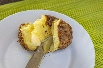 Potatoes from the fire with butter and salt on a plate, grilled dishes, grilled potatoes in their skins