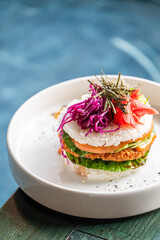 A visually striking dish featuring a layered rice sandwich, garnished with vibrant vegetables and...