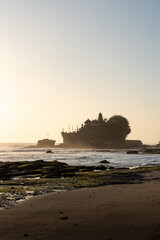 Tanah lot temple standing on a rock formation in the ocean at sunset in bali, indonesia