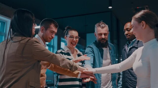 Business professionals stacking hands in support of collaboration, inclusion, and equality in the office. The workplace community huddles together for solidarity, cooperation, and team building.