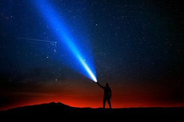 Illustration. A person shining a flashlight into the night sky