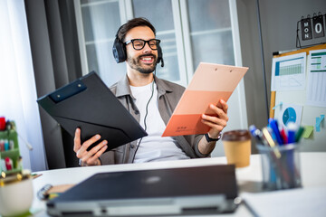 Young man with headphones choosing between two projects.