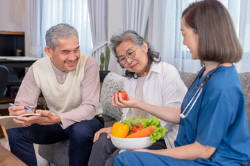 home health care nurse in uniform explaining nutritional value of fruits,vitamins and dietary fiber to senior couple,old man writing on notebook