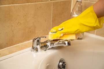 Cleaning bathroom water tap, yellow gloves and spray detergent