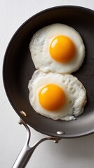 Two perfectly cooked sunny-side-up eggs in black frying pan – perfect for breakfast branding, protein content or food visuals emphasizing simplicity, clarity and freshness