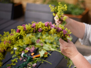 The hands of a woman building a midsummer wreath of flowers for the traditional swedish midsummer...