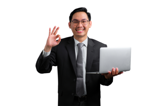 Happy young Asian businessman showing okay gesture while holding laptop isolated on transparent background
