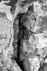 Partial collapse of ancient stone wall with large depression and crack. Old stonework with limestone surface darkened by time and partially covered with moss. Copy space for text.