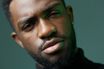 Fototapeta premium Pensive bearded man bathed in green light, contemplating in lowkey lighting