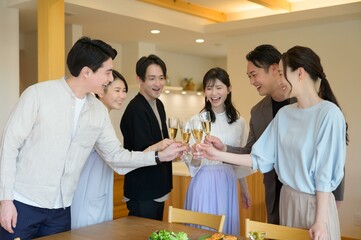 若い男女のグループがテーブルを囲んで楽しく乾杯しているパーティーの一幕