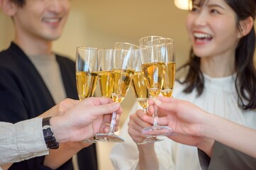 笑顔でグラスを掲げながら楽しそうに乾杯する若い男女の集まり