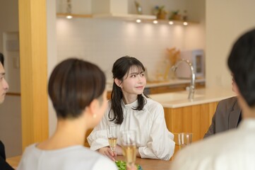 若い女性がグラスを片手に周囲と会話を楽しみながら落ち着いた笑顔を見せる瞬間