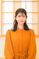 正面を見つめる女性が和室の明るい背景で微笑む
