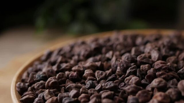 Raw Dark Brown Chickpeas (Kala Chana) on a rustic wooden table. Dry Balck chickpea (ceci neri) background close up. 