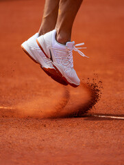 Tennis player leaping, kicking up dust