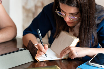 Young woman writing notes on notebook at home or office desk