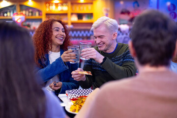 Happy couple toasting with water and enjoying meal at restaurant