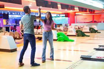 Friends giving high five celebrating bowling game in alley