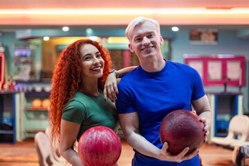 Happy couple holding bowling balls, ready for a fun night out