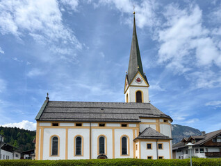 Catholic Church Pfarrkirche Angath in Tyrol, Austria, with Mountain Background and Cloudy Sky