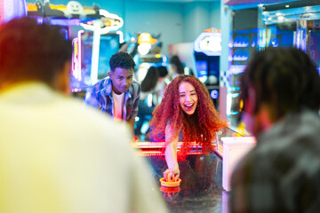 Friends playing air hockey, having fun together at the arcade center
