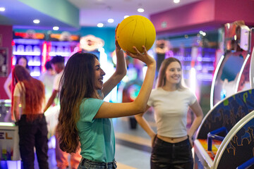 Young women playing basketball in amusement arcade