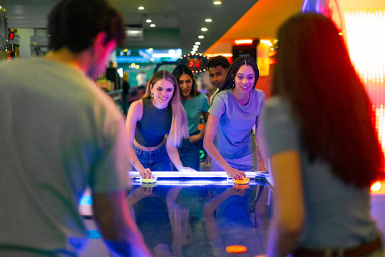 Friends playing air hockey in arcade games room