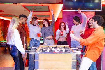 Friends celebrating winning a foosball match in a pub