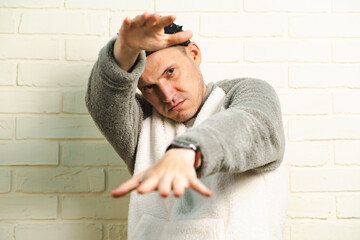 A man wearing a black cap and a gray sweater is captured in motion, dancing gracefully with fluid...