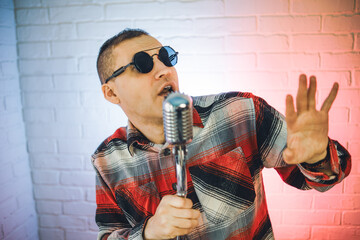 A man wearing a plaid shirt enthusiastically sings into a microphone, showcasing his passion for...
