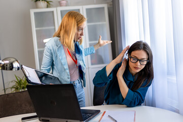 Woman yelling at a colleague in an office, showing workplace bullying.