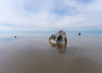 Remains of wooden piles covered with salt reflecting in the calm waters of Lake Elton