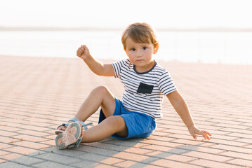 Cheerful Little Boy Sitting Outdoors on a Sunny Day