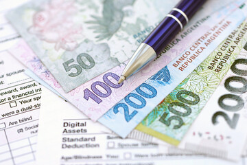 Argentine pesos money bills in big amount lies on table with pen and tax forms close up