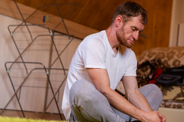 A professional sportsman is seated on a on the floor, engaging in legs stretches as part of his...