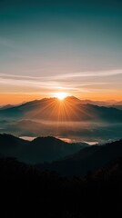 Fototapeta premium Breathtaking Sunrise Over Mountain Range with Rays of Light Illuminating the Horizon and Misty Valley Below
