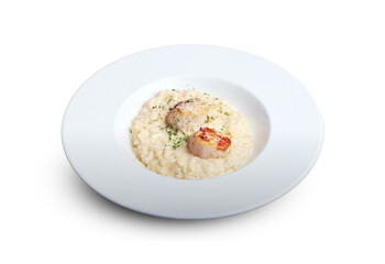 Creamy risotto served with seared scallops and garnished with herbs on a white plate, isolated on white background.