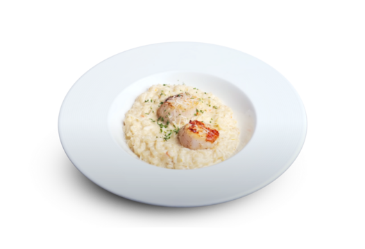 Creamy risotto served with seared scallops and garnished with herbs on a white plate, isolated on white background.