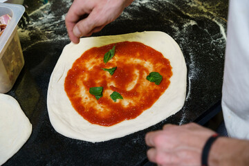 Adding fresh basil to pizza dough