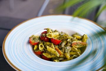 Penne pasta with pesto sauce and cherry tomatoes