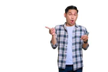 Shocked young Asian man in plaid shirt holding mobile phone and pointing fingers aside at copy space isolated on transparent background