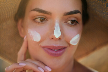 A woman smile applying sun cream on face. Skincare. Body Sun protection.  Female smear sunscreen moisturizing lotion on skin. Beauty skin care concept