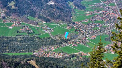 View from the Wallberg of a flying paraglider against the town of Gmund in the background