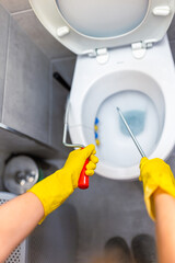 A close-up shot of a young woman applying drain cleaner to a clogged toilet bowl.