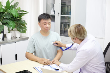 Fototapeta premium Doctor performs medical checkup on patient using stethoscope in clinic