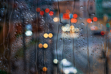 raindrops on the window and multi colored street lights at night background