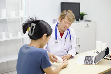 Doctor in white coat attentively examines patient hand in medical office