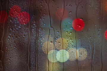 raindrops on the window and multi colored street lights at night background